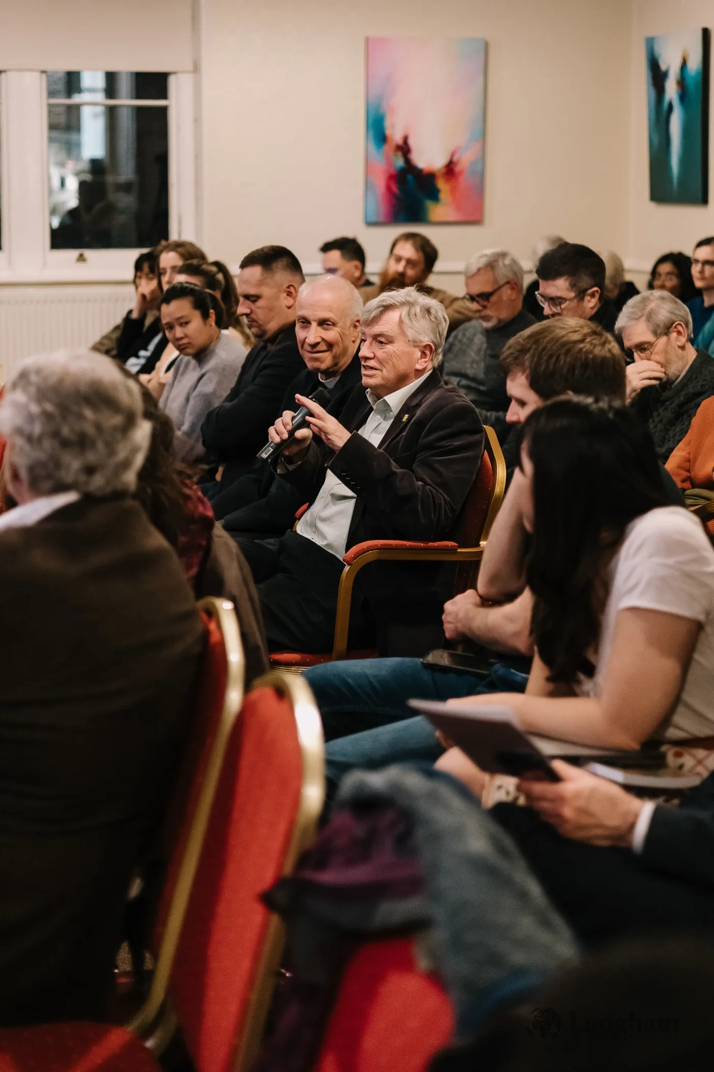 An attendee putting a question to the panel with a microphone during the discussion.